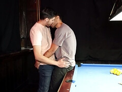 Two men with big cocks are banging a lad on the table