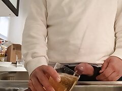 Desperate pee in a glass in the kitchen