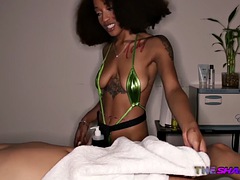 Tattooed ebony masseuse jerks off cock during erotic massage