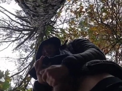 Bulky bodybuilder is milking off in woods outdoor public place