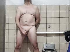 More old guy naked and masturbating in big men's room stall