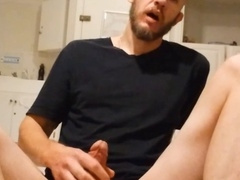 Hunky guy strokes his throbbing member while sitting on the floor