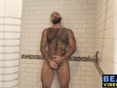 Muscular man soaps up his hairy body and pleasures his sizable manhood