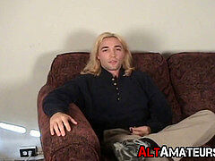 Classy stud with lengthy platinum-blonde hair working on his lollipop