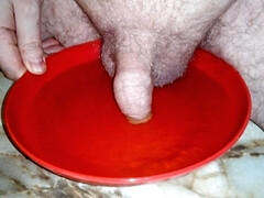 John is peeing on a plate with the cock in the pee