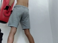 Slim twink with a massive hard-on pounds the punching bag and cums on the gloves