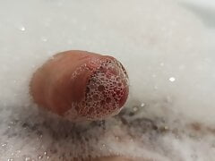 Close up pissing cock from the foam in bath tube