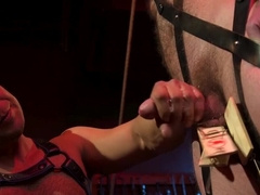 Tied up behind bars and getting his erect cock jerked off